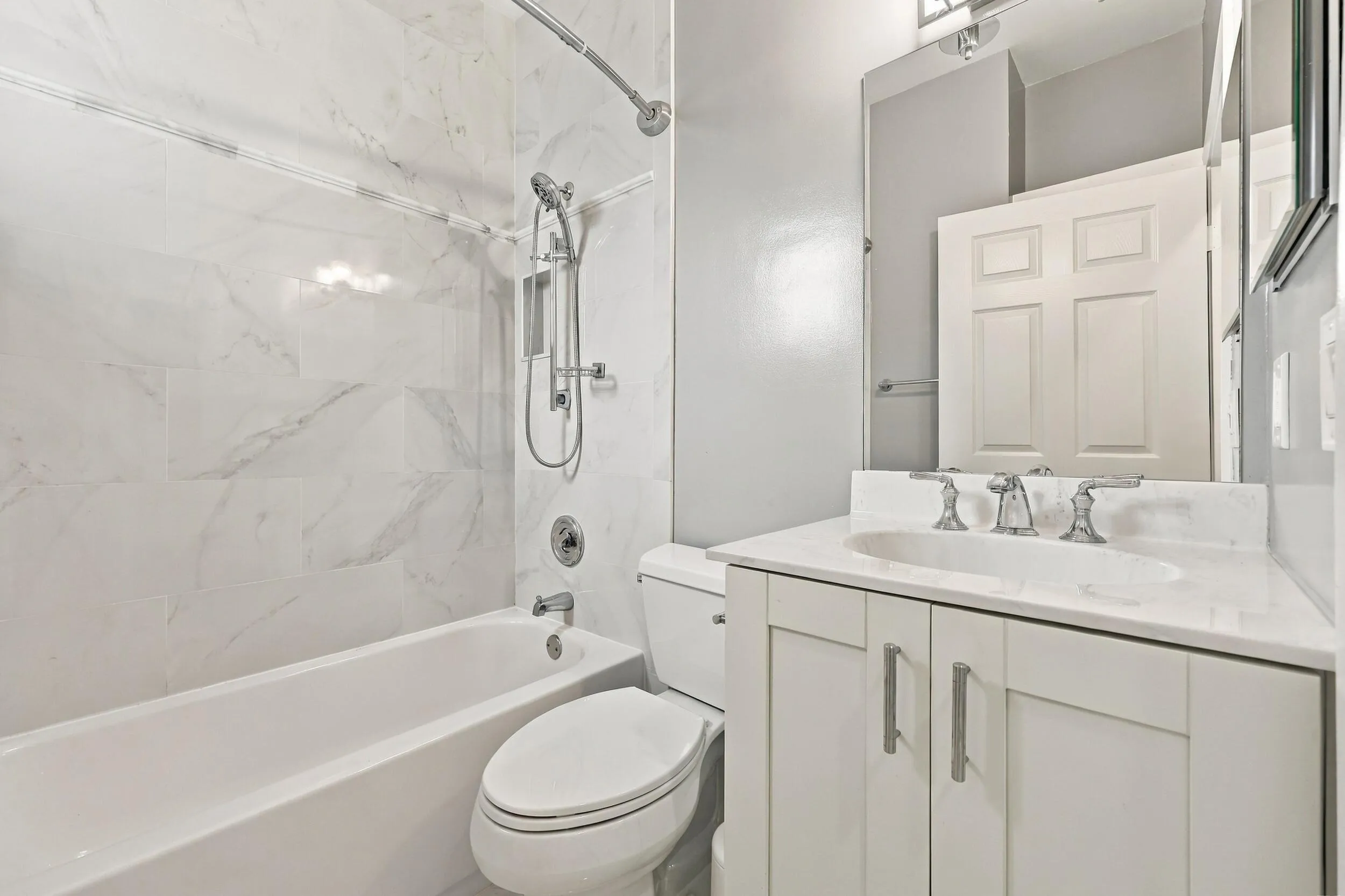 White vanity with brushed nickel hardware, undermount sink, and light-toned countertop