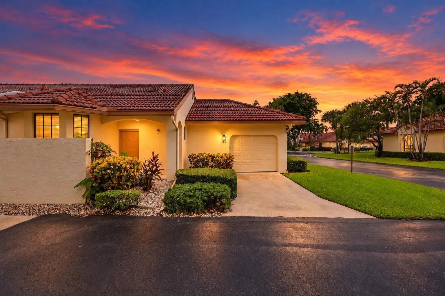 Mediterranean-style exterior with a terra cotta tile roof, light-colored stucco finish, and an attached garage