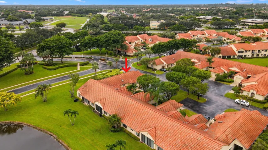 Residential buildings with terra cotta tile roofs, green landscaping, and a water feature