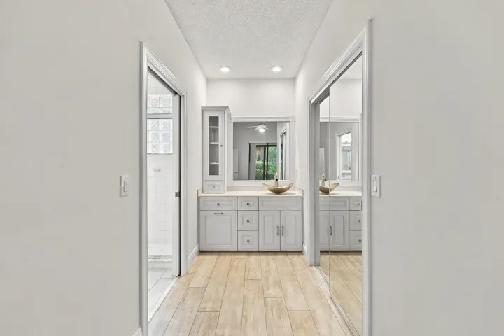 Hallway with wood-finish flooring, recessed lighting, white walls, and mirrored closet doors