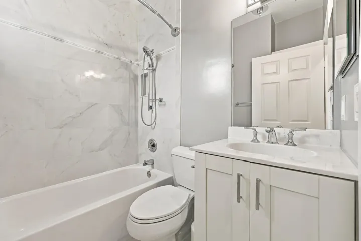 White vanity with brushed nickel hardware, undermount sink, and light-toned countertop