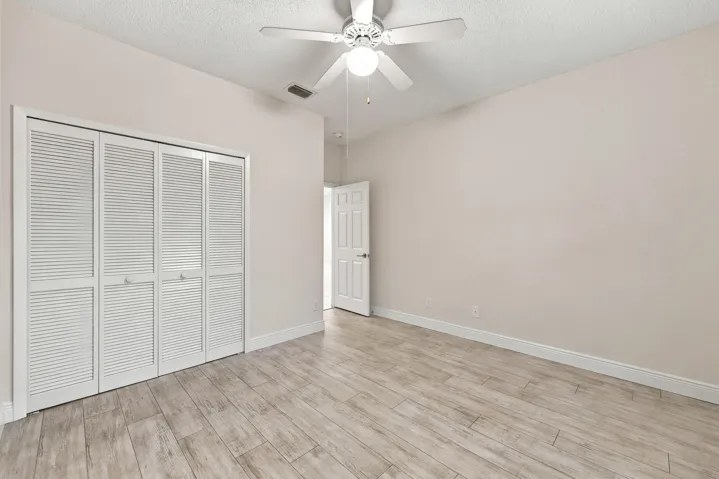 Wood-finish flooring throughout, complemented by a white ceiling fan with integrated lighting