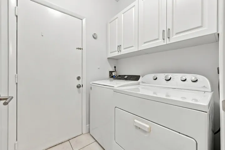 Laundry area with white cabinetry, tile flooring, and a white door