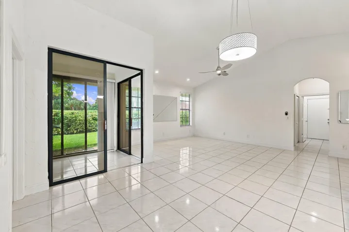 Expansive interior featuring large format tile flooring, vaulted ceilings, and a modern ceiling fan