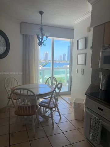 Tile flooring, sliding glass door, crown molding, built-in microwave, and water scenery
