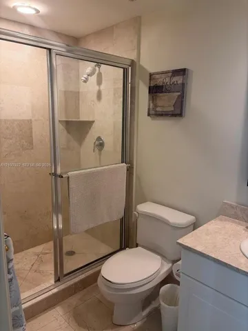 Tiled shower enclosure with a glass door, built-in shower shelf, and a recessed light fixture