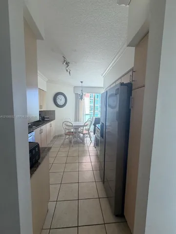 Kitchen featuring tile flooring, light wood-finish cabinetry, dark countertops, and stainless steel appliances