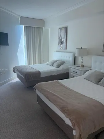 Plush carpeted flooring, window treatments, white walls, and crown molding