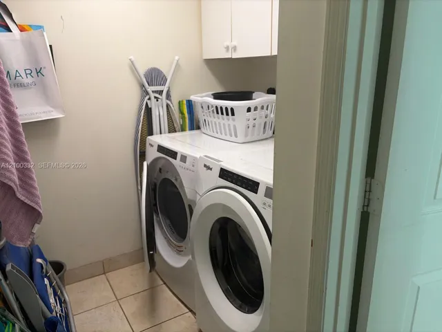 Laundry area featuring white cabinetry, tiled flooring, and a full-size washer and dryer
