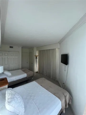Neutral wall color, wall-mounted television, full-height window treatments, and white paneled wardrobe doors