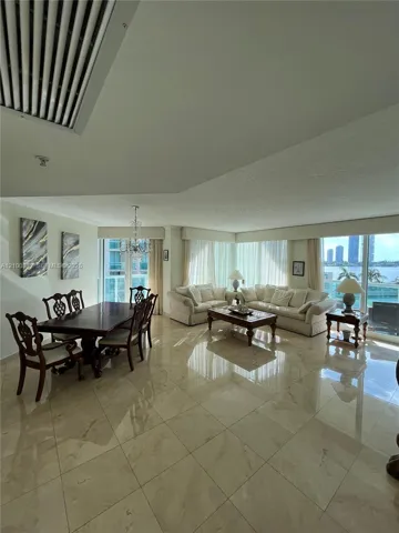 Expansive open-concept living area featuring large format tile flooring, a recessed ceiling light, and ample natural light from multiple windows