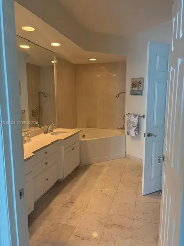 Dual vanity with integrated sinks, corner soaking tub, and a separate shower enclosure with tiled walls