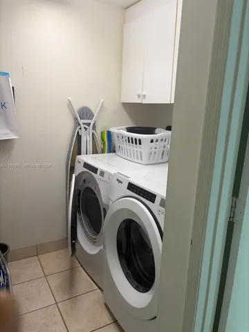 Front-loading washer and dryer, upper cabinetry, and tile flooring