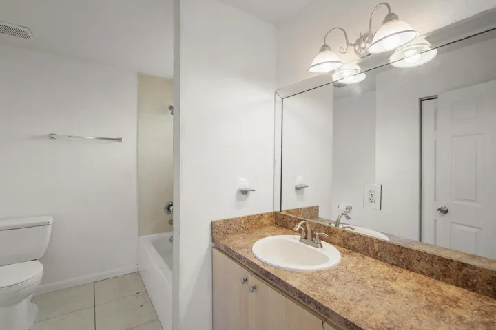 Bathroom featuring a vanity with a stone-finish countertop, undermount sink, and full-width mirror
