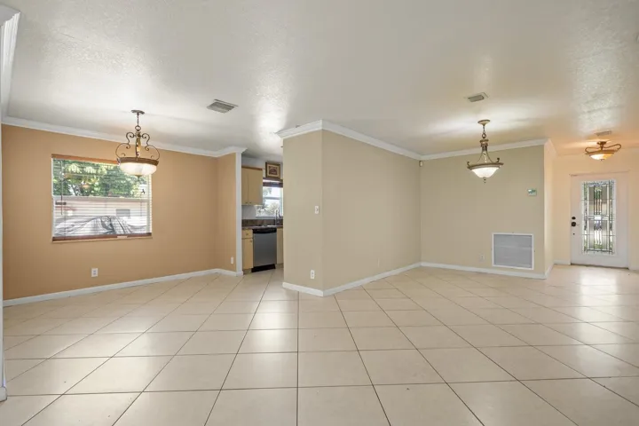 Tiled flooring throughout, decorative ceiling light fixtures, crown molding, and a kitchen featuring stainless steel appliances and wood-finish cabinetry