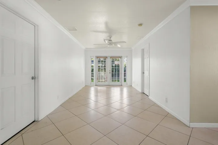 Tiled flooring, white interior walls, white paneled doors, ceiling fan, and French doors with sidelights