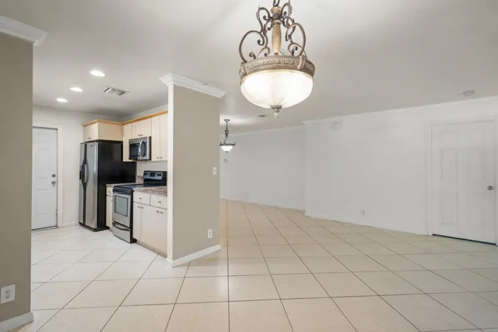 Tile flooring throughout, kitchen with light wood-finish cabinetry, stainless steel appliances, and recessed lighting