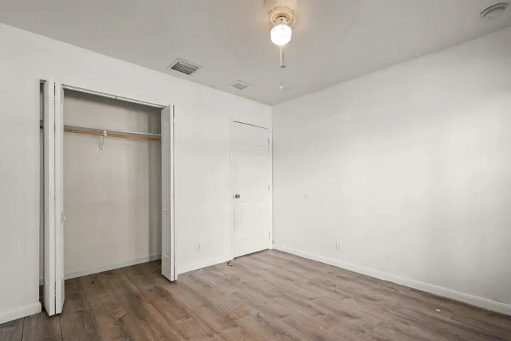Wood-finish flooring, ceiling fan with integrated lighting, and a built-in closet with bi-fold doors