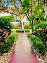 Manicured landscaping with a paved pathway, mature trees, and lush greenery