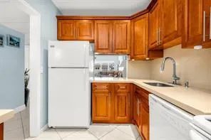 Kitchen featuring wood-finish cabinetry, light-toned countertops, and a stainless steel gooseneck faucet