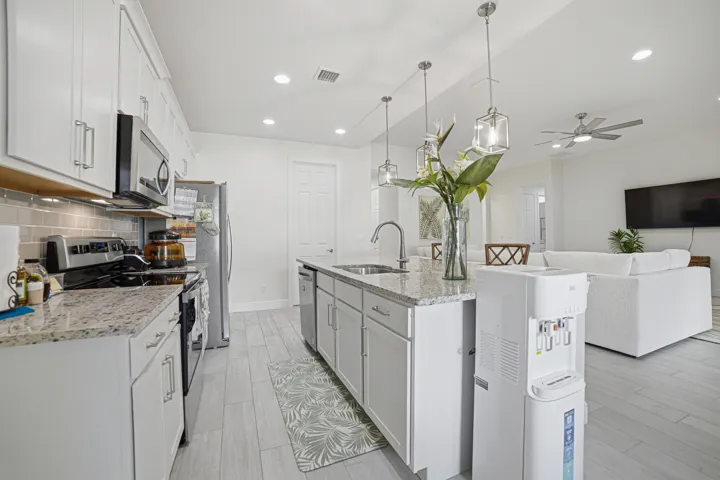 Kitchen with white cabinetry, stainless steel appliances, granite countertops, tile backsplash, and wood-finish flooring