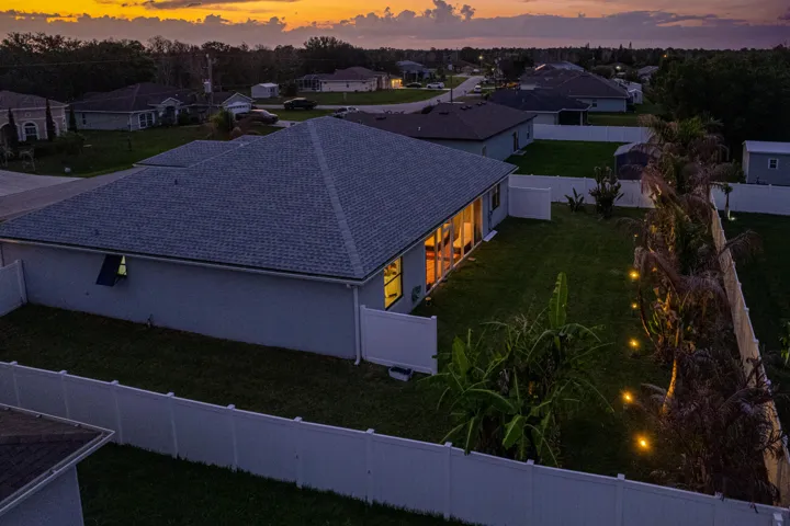 Fenced backyard with manicured lawn and string lighting