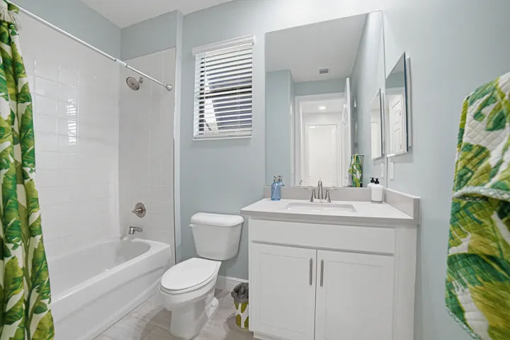 White tiled shower with a tub, a toilet, a vanity with a white countertop, and a large mirror