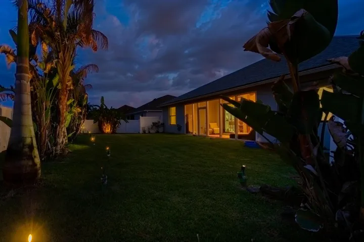 Expansive backyard with manicured lawn and mature tropical landscaping