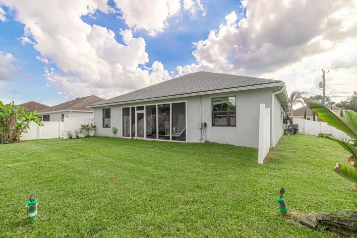 Expansive green lawn, screened-in patio, white privacy fencing, and grey exterior siding