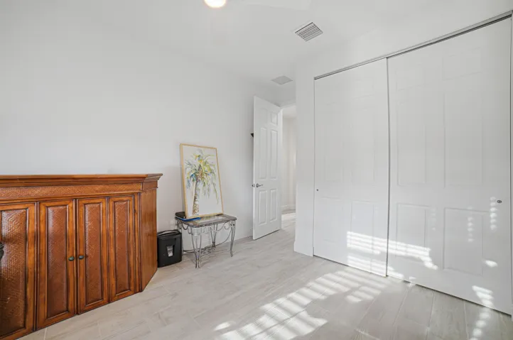 Recessed lighting, wood-finish flooring, white paneled bifold closet doors, and a white interior door