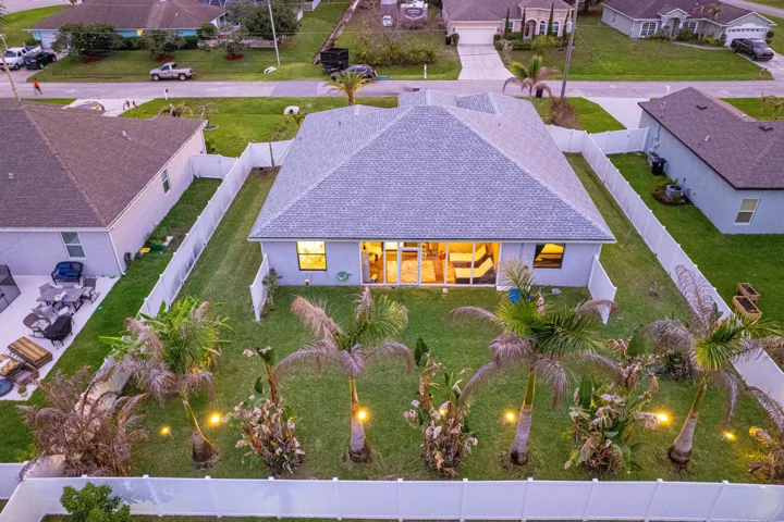 Expansive backyard featuring a manicured lawn, mature palm trees, and a full privacy fence