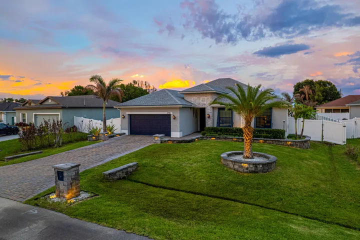 Single-story residence featuring a paver driveway, an attached two-car garage, and a fenced side yard