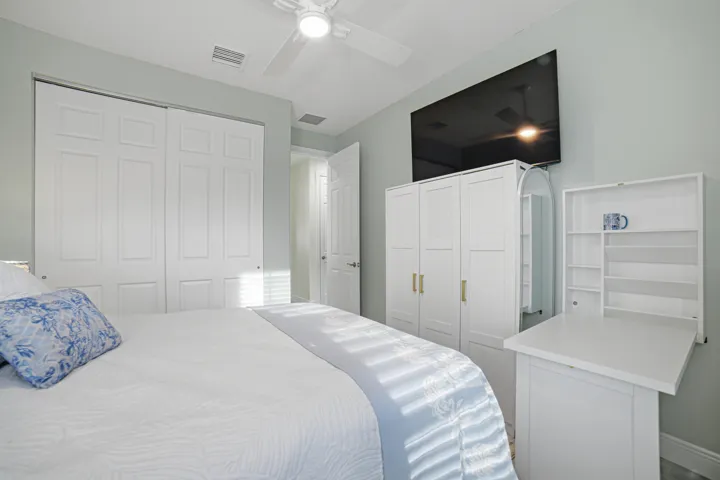 Ceiling fan with light fixture, double closet with bifold doors, and a built-in wall desk with shelving