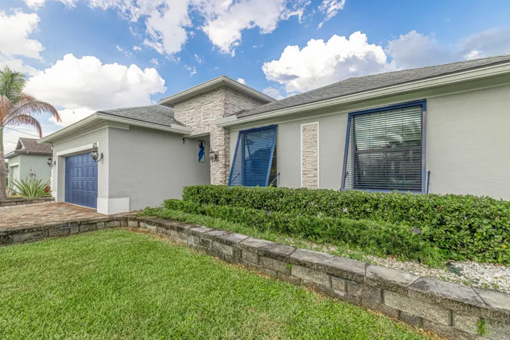 Exterior featuring a blue panel garage door, stone façade accents, and blue exterior window panels