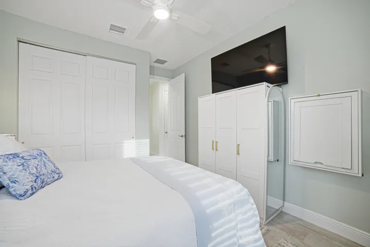 White paneled closet doors, ceiling fan, wood-finish flooring, and light-toned walls