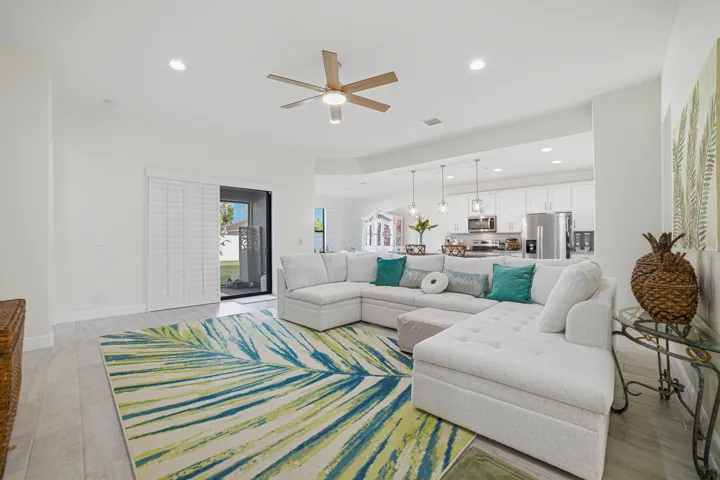 Recessed lighting, wood-finish flooring, sliding glass doors with louvered shutters, and a ceiling fan with integrated lighting