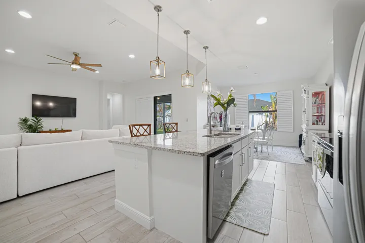 Open-concept kitchen featuring an island with a stone counter, recessed lighting, wood-finish flooring, and pendant lighting