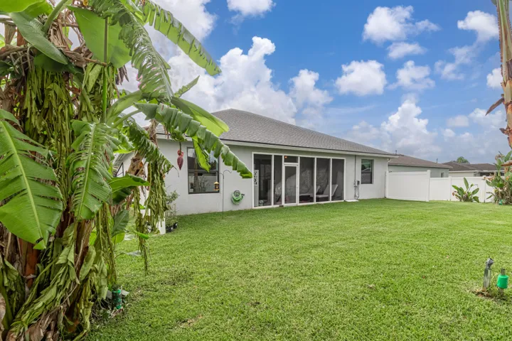 Expansive backyard featuring a screened-in patio, stucco exterior, shingle roof, and a white privacy fence