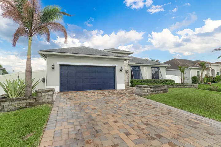Paver driveway leading to a two-car garage with a paneled door