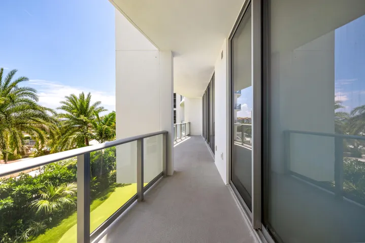 Expansive private balcony with glass panel railing and sliding glass doors