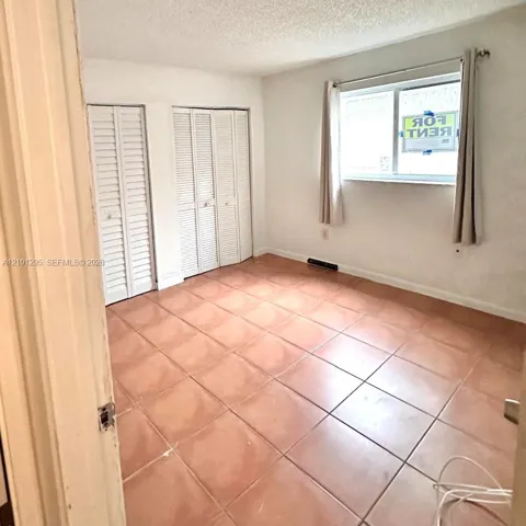 Interior room featuring ceramic tile flooring, dual white louvered closet doors, and a horizontal sliding window