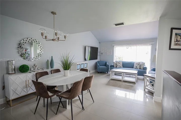 Dining area with a statement chandelier, open to the living room.