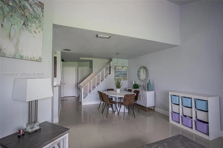 Open dining and living layout under dramatic two story ceiling volume.
