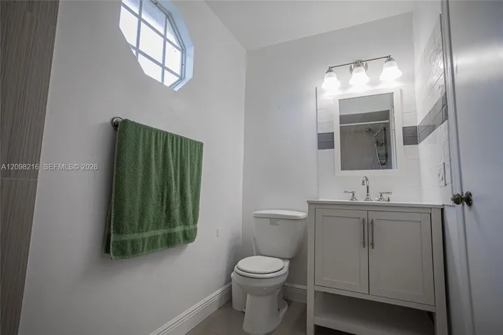 Bathroom with a crisp white vanity and a round accent window.