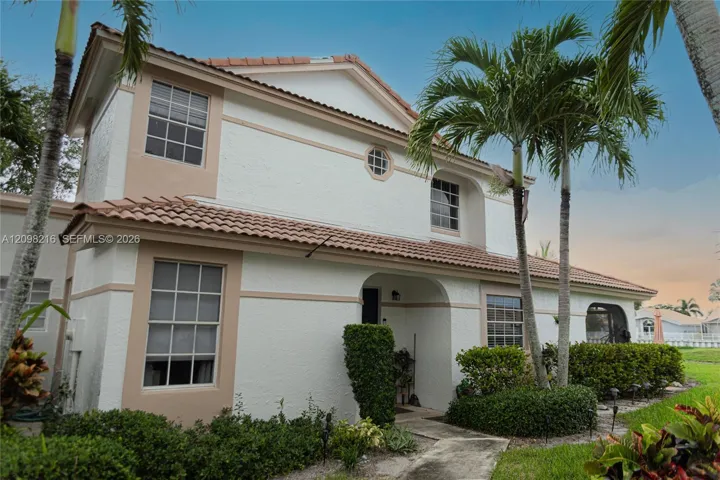 Classic two story Mediterranean style exterior framed by tropical palms.