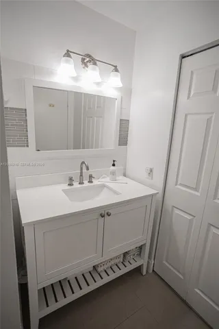White vanity with an open lower shelf and modern lighting.