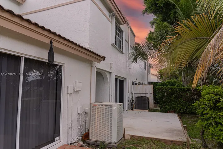 Side exterior with a private patio and sliding glass access.