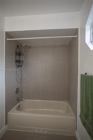 Tub and shower combination finished in neutral tile.