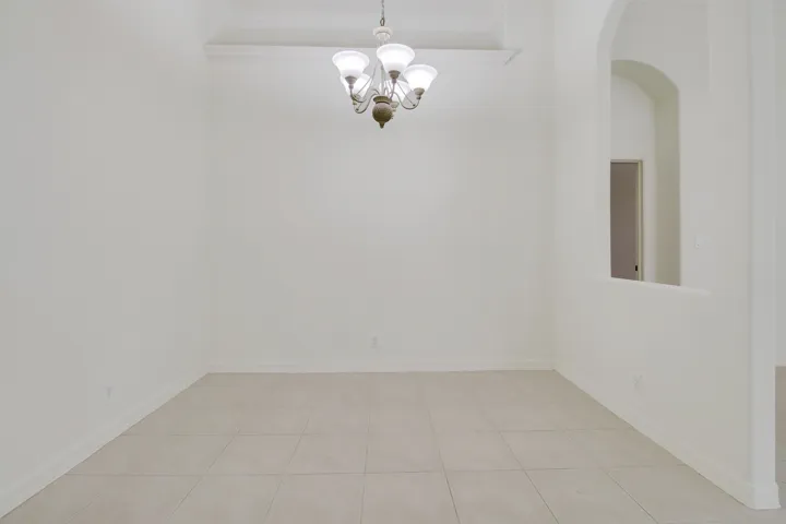 Tiled flooring, vaulted ceiling, arched wall opening, and neutral wall tones