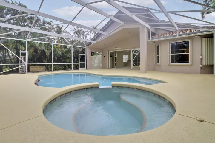 Screened-in outdoor area with a freeform pool and integrated spa